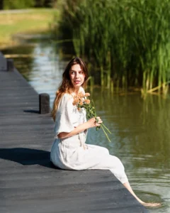 Modelka siedząca na pomoście w lnianej sukience z kolekcji Naturalnie Podlasek