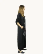Czarna maxi lniana sukienka oversize, ozdobiona ręcznie malowanymi dmuchawcami, uszyta przez Naturalnie Podlasek, widok z boku
