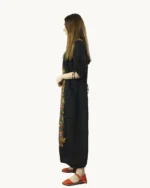 Czarna maxi lniana sukienka oversize, ozdobiona ręcznie malowanymi wzorami, uszyta przez pracownię Naturalnie Podlasek, widok z boku