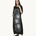 Czarna maxi lniana sukienka oversize, ozdobiona ręcznie malowanymi dmuchawcami na kontrastowym tle, uszyta przez pracownię Naturalnie Podlasek, widok z przodu