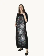 Czarna maxi lniana sukienka oversize, ozdobiona ręcznie malowanymi dmuchawcami na kontrastowym tle, uszyta przez pracownię Naturalnie Podlasek, widok z przodu