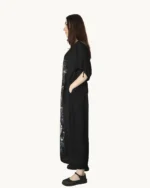 Czarna maxi lniana sukienka oversize, ozdobiona ręcznie malowanymi dmuchawcami na kontrastowym tle, uszyta przez pracownię Naturalnie Podlasek, widok z boku