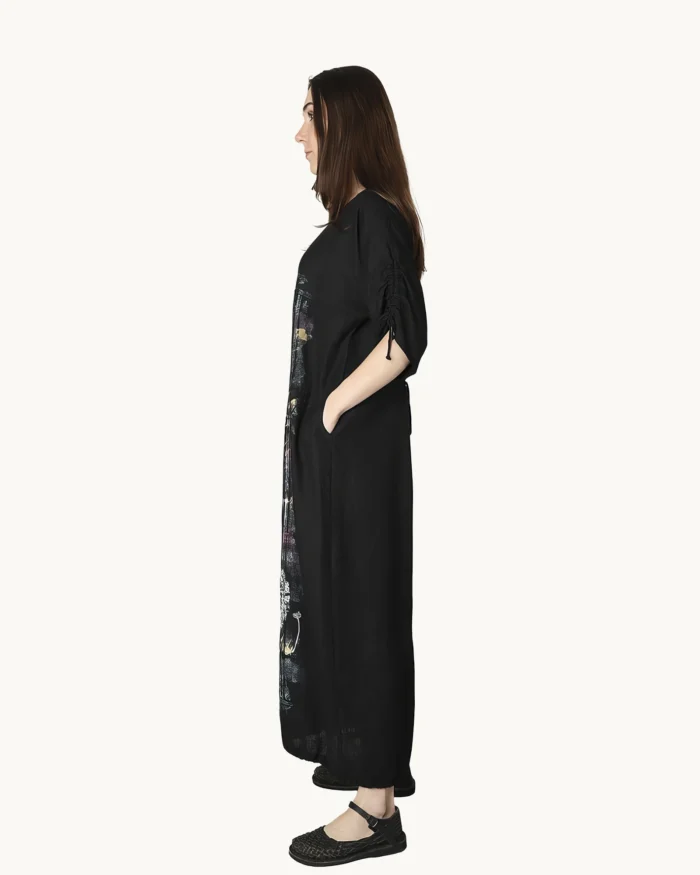 Czarna maxi lniana sukienka oversize, ozdobiona ręcznie malowanymi dmuchawcami na kontrastowym tle, uszyta przez pracownię Naturalnie Podlasek, widok z boku