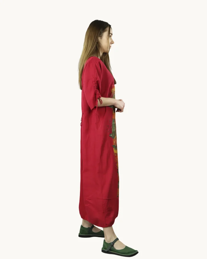 Czerwona maxi lniana sukienka oversize, ozdobiona ręcznie malowanymi kwiatowymi wzorami na kolorowym tle, uszyta przez pracownię Naturalnie Podlasek, widok z boku