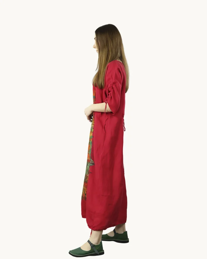 Czerwona maxi lniana sukienka oversize, ozdobiona ręcznie malowanymi kwiatowymi wzorami na kolorowym tle, uszyta przez pracownię Naturalnie Podlasek, widok z boku