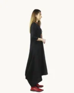 Czarna lniana sukienka oversize o luźnej, swobodnej formie z wyraźnie zaznaczoną asymetrią dołu, ozdobiona ręcznie malowanymi wzorami, widok z boku