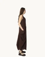 Brązowa lniana sukienka maxi typu oversize o asymetrycznym kroju, krótkim rękawem, ozdobiona ręcznie malowanymi wzorami, widok z boku