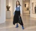Modelka w ręcznie malowanej sukience ogrodniczce z jeansu i czarnej dzianiny we wnętrzu galerii