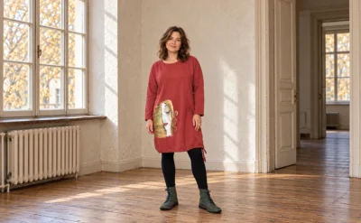 Modelka w rozmiarze L/XL prezentuje ręcznie malowaną krótką sukienkę dzianinową oversize